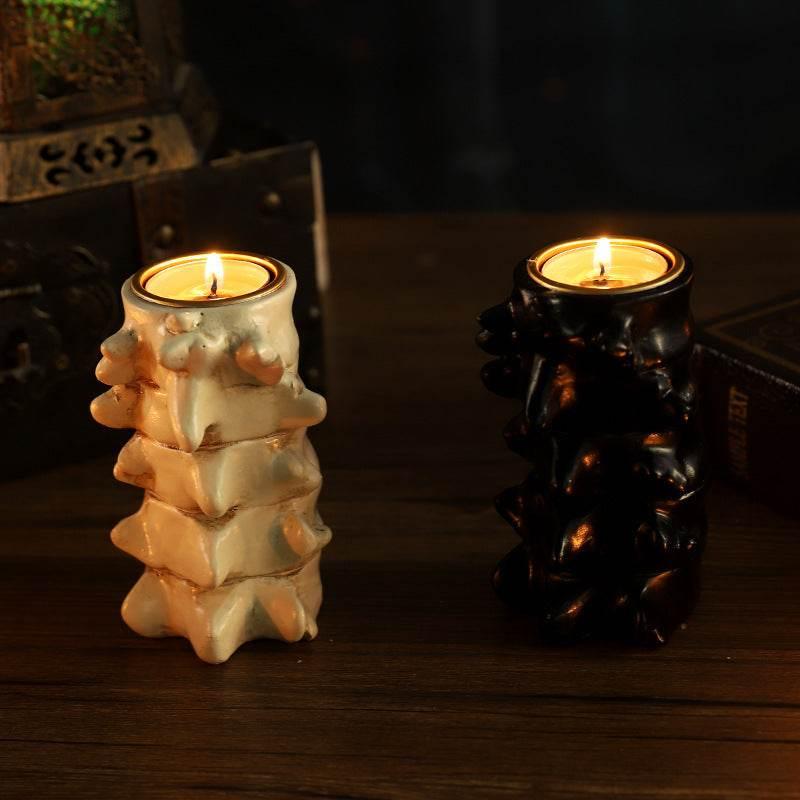 White and black spine-shaped candles with flames lit on wooden table, gothic home decor