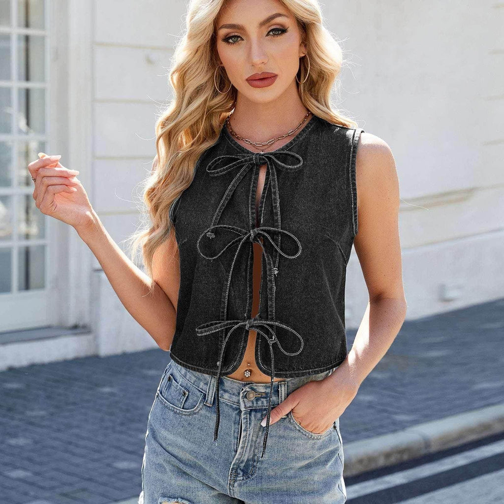 Woman in sleeveless black denim tie-front top and ripped jeans, trendy street style fashion
