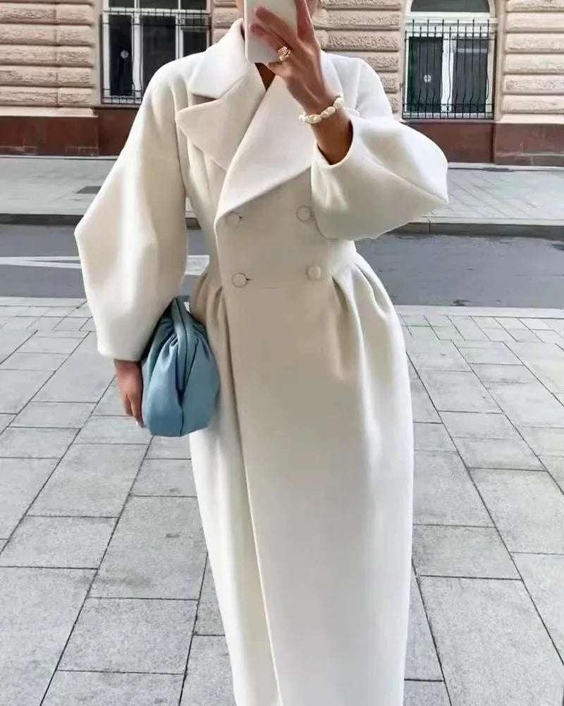Woman wearing long white wool coat with puffy sleeves, holding light blue handbag outdoors
