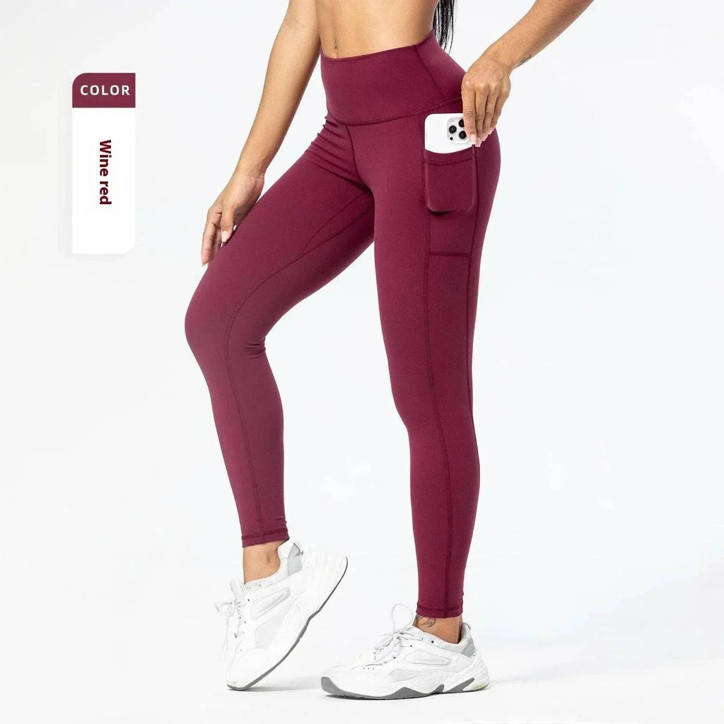 Woman wearing high-waisted wine red leggings with side pocket and white sneakers