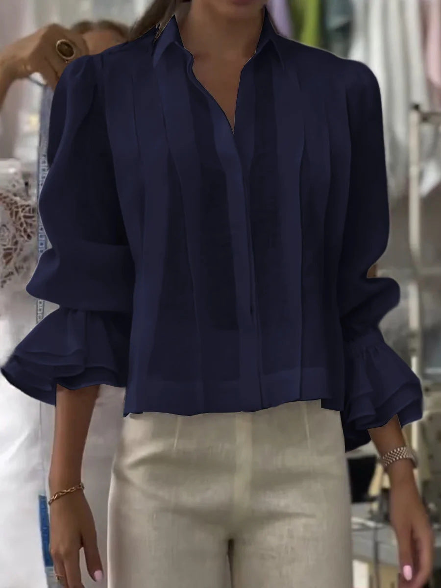 Navy blue blouse with ruffled sleeves worn by a person, blurred background