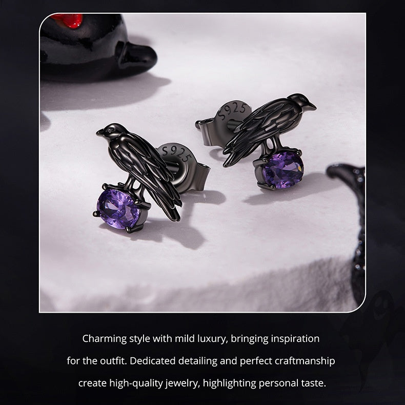 Black bird-shaped cufflinks with purple gemstones on a white surface.