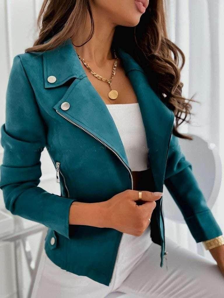 Woman wearing teal moto jacket over white top, gold pendant necklace, modern casual fashion