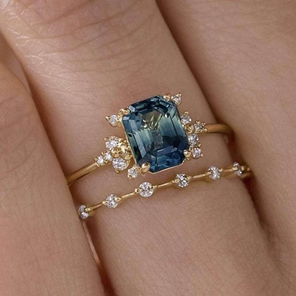Gold ring with large blue gemstone and diamond accents on hand, delicate stacking design