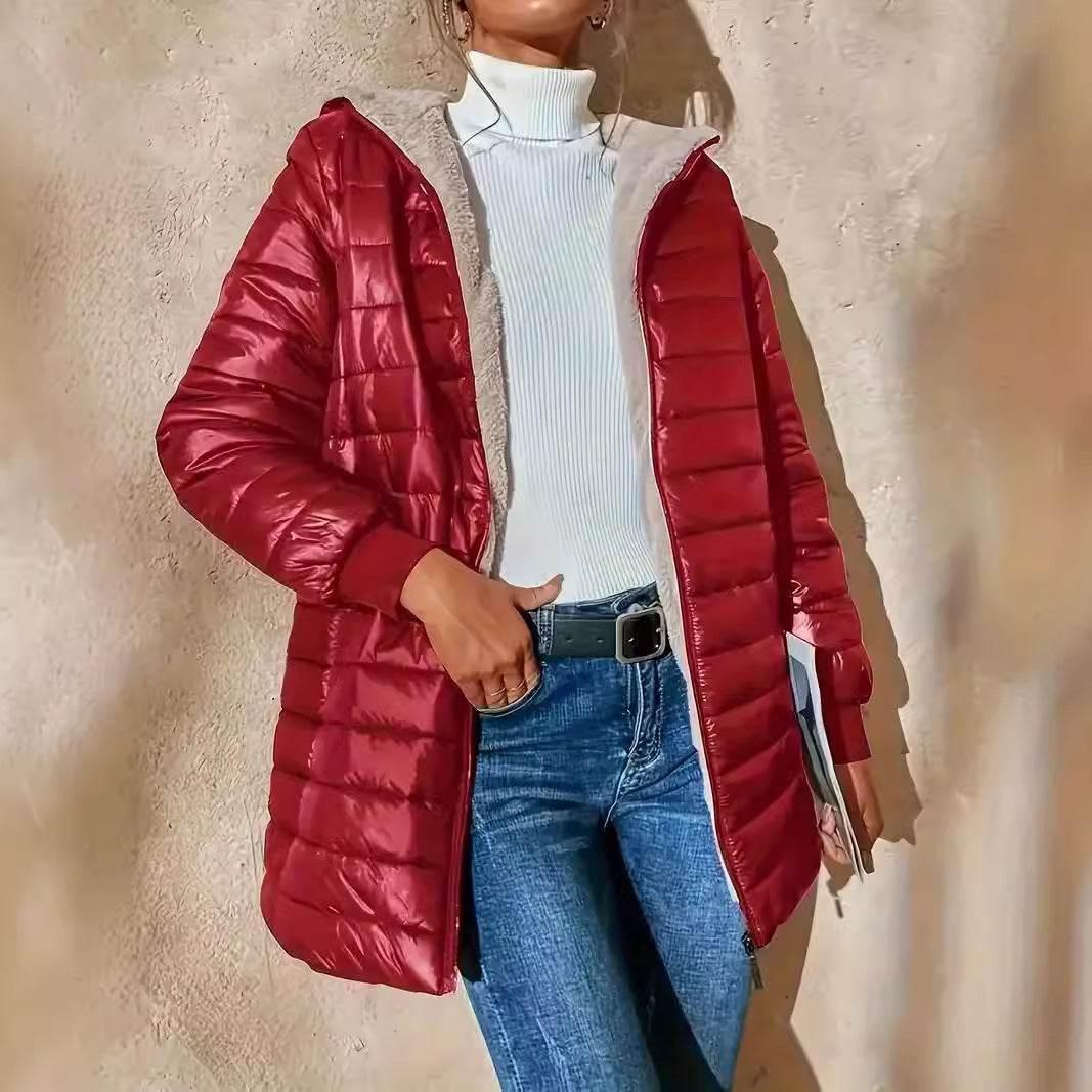 Woman modeling a shiny red puffer jacket with hood, white turtleneck, and blue jeans