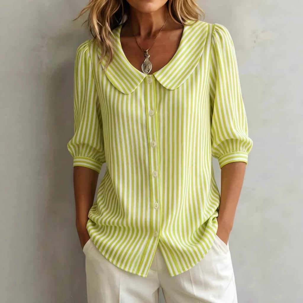 Woman wearing a green and white striped shirt with a plain background