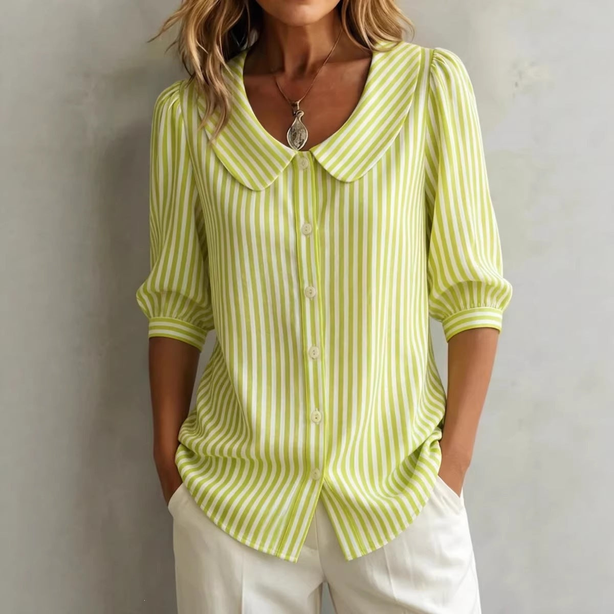 Woman wearing a green and white striped shirt with a plain background
