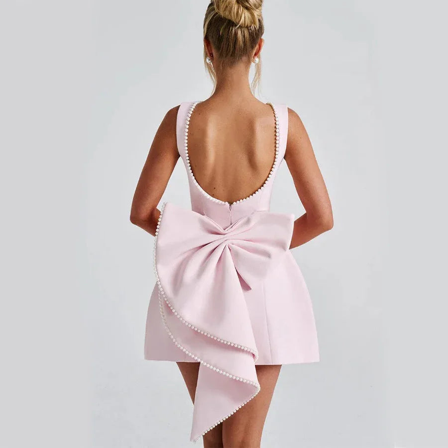 Pink dress with a large bow detail on a plain background