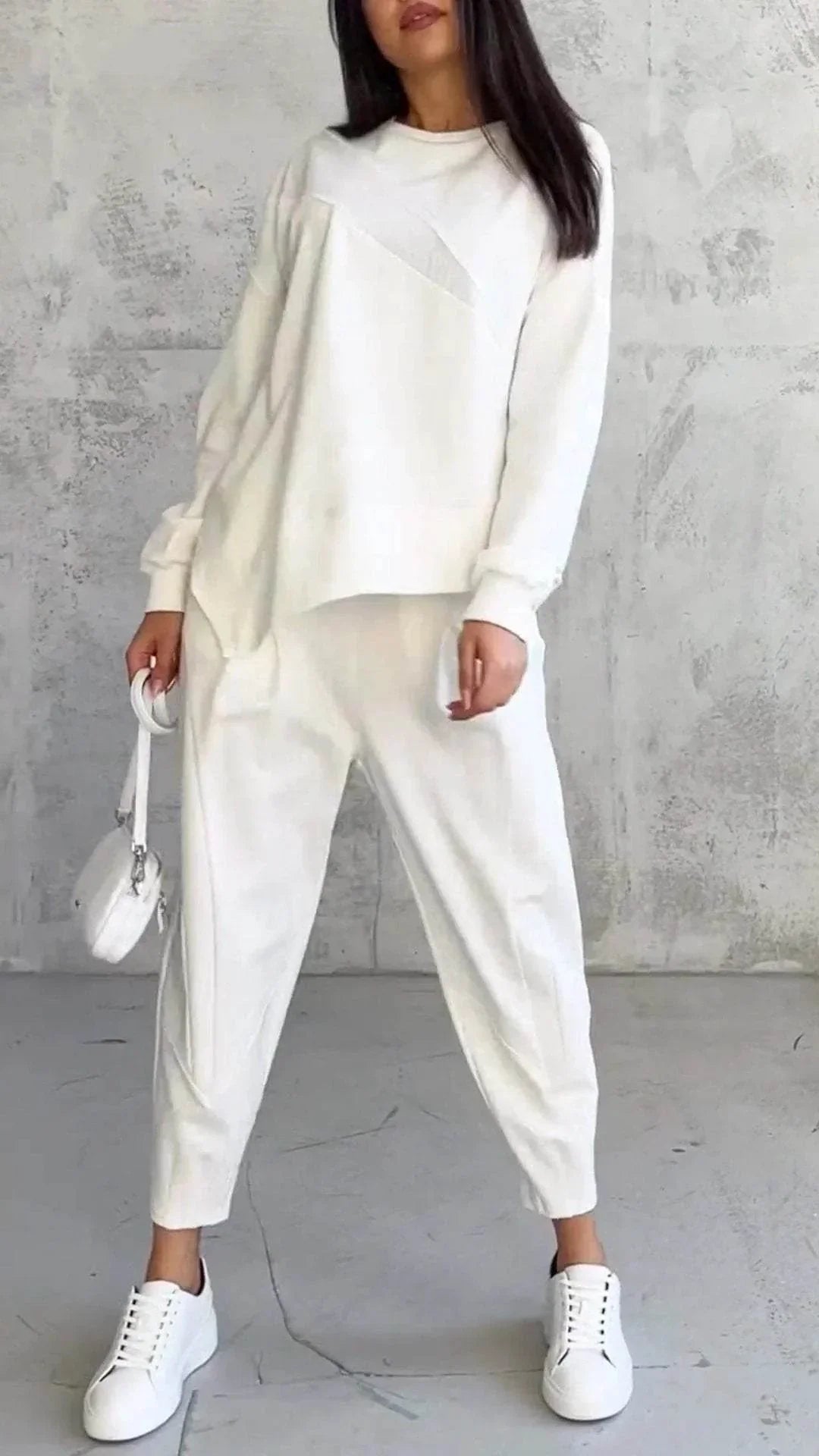 Woman in white casual lounge set with joggers, sweatshirt, sneakers and mini crossbody bag