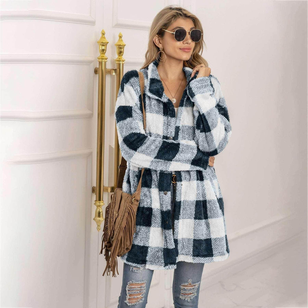 Woman wearing black and white checkered fleece coat, ripped jeans, and sunglasses indoors