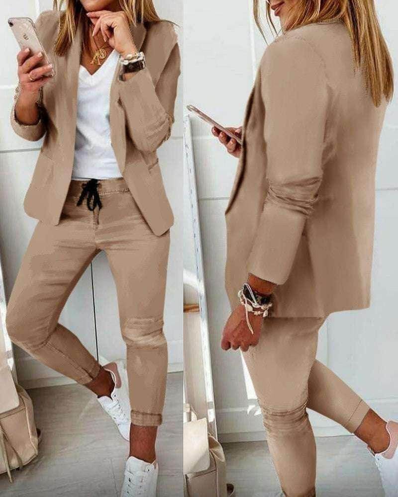Woman wearing beige blazer and pants set with a white V-neck top and white sneakers