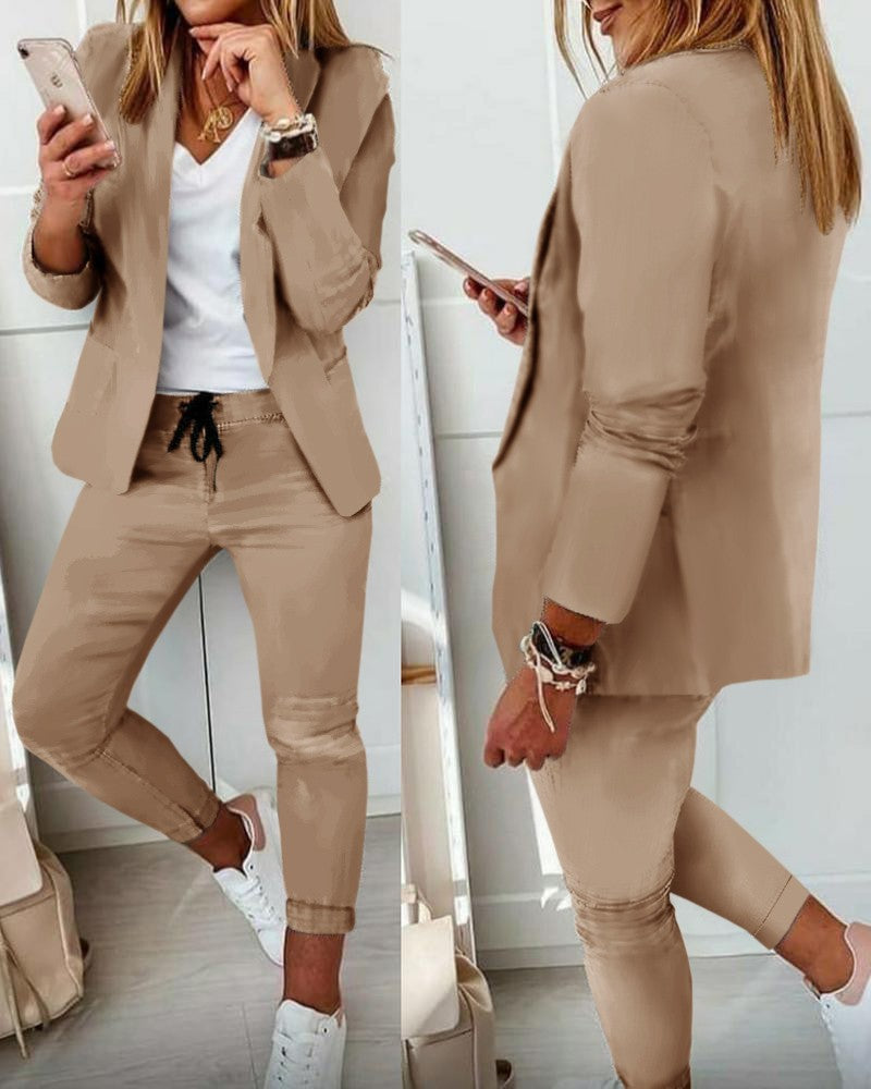 Woman in a beige suit looking at her phone in a minimalistic setting
