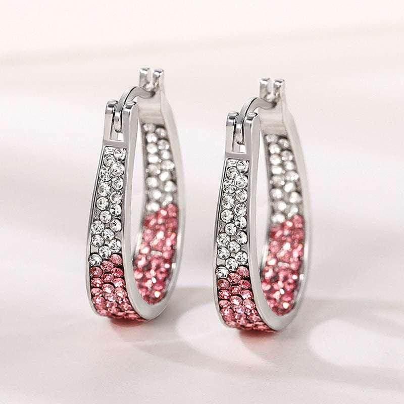 Silver hoop earrings with white and pink crystals, stylish women's jewelry on light background.
