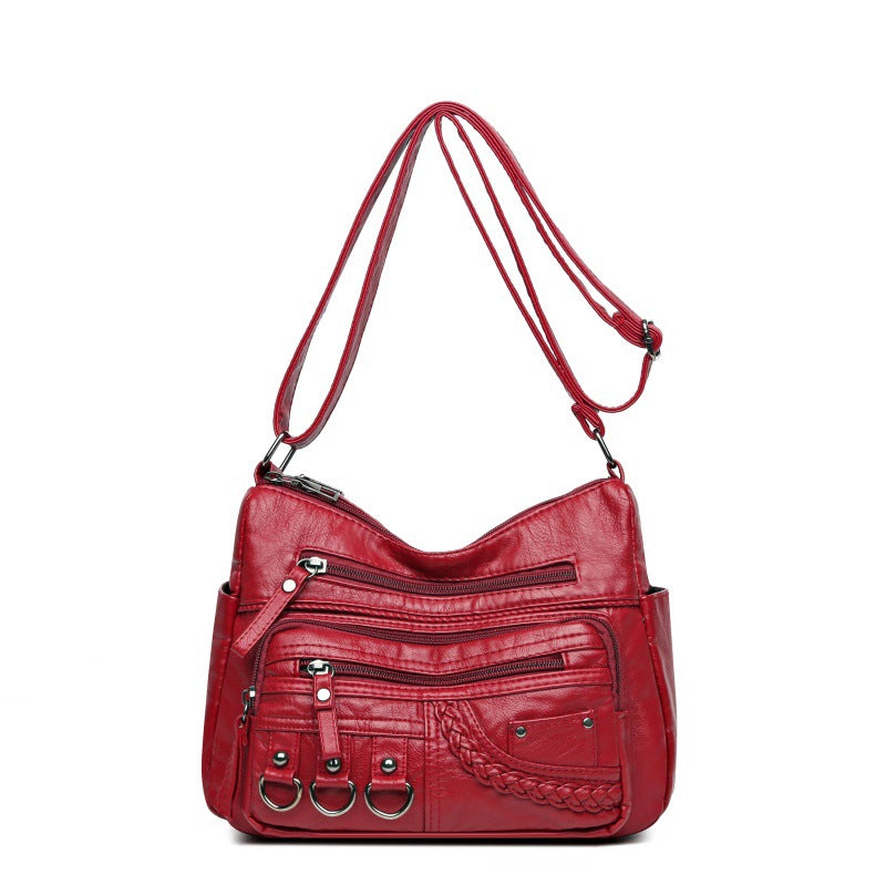 Red handbag with multiple zippers on a white background