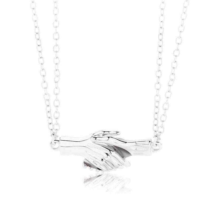 Silver necklace with two clasped hands pendant on a delicate chain, stylish jewelry accessory