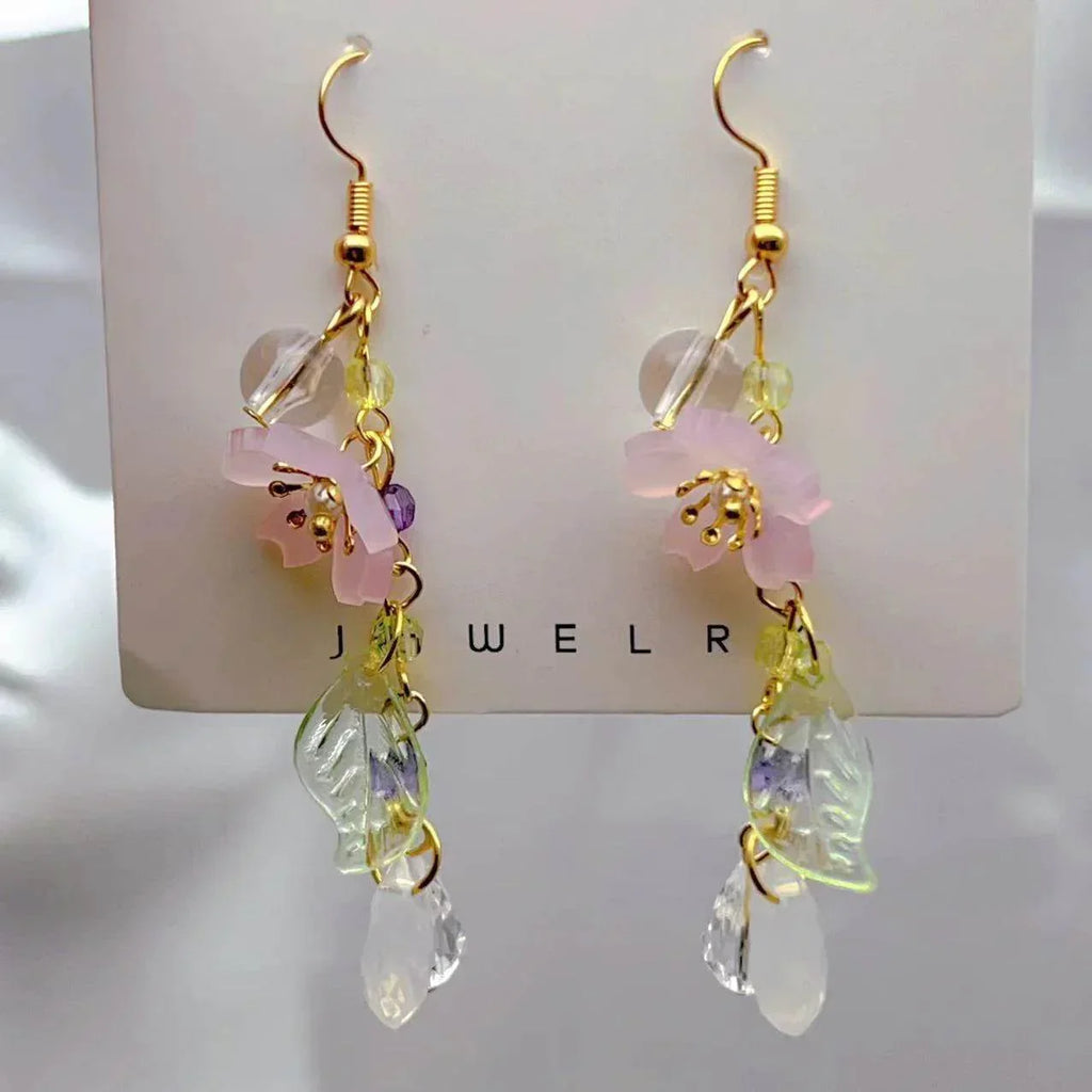 Dangling gold earrings with pink flower, crystal beads, and leaf charms on display card