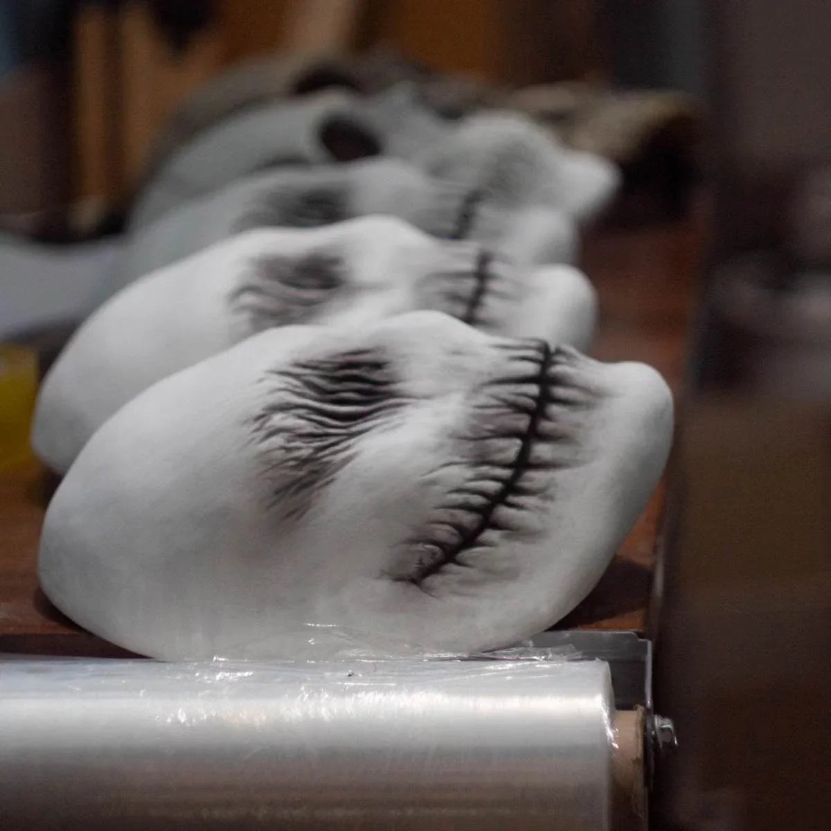 Realistic white costume masks with stitched black mouth details lined up on a table