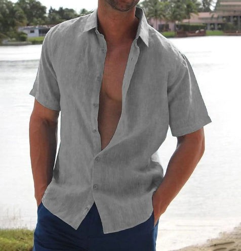 Man wearing an open gray shirt with a blurred natural background