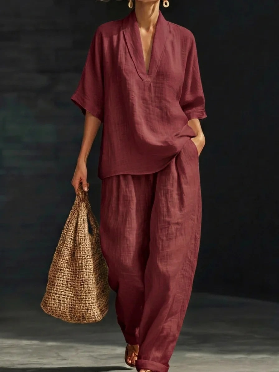 Person wearing a maroon outfit holding a woven bag against a dark background