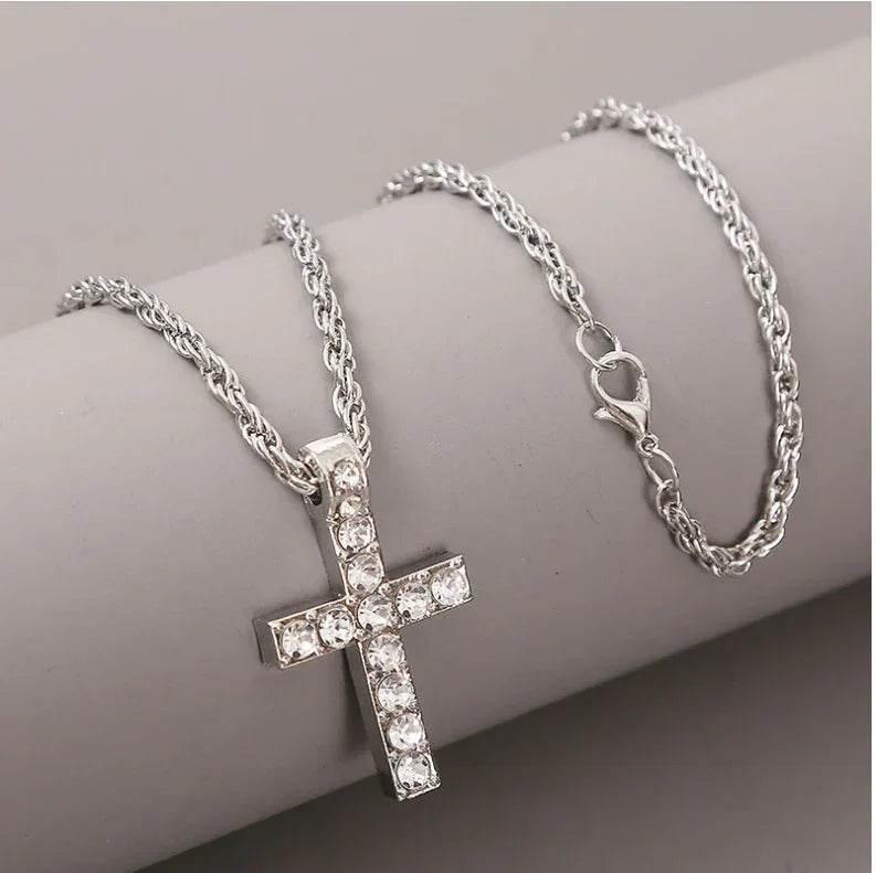 Silver chain necklace with crystal cross pendant, displayed on a grey background