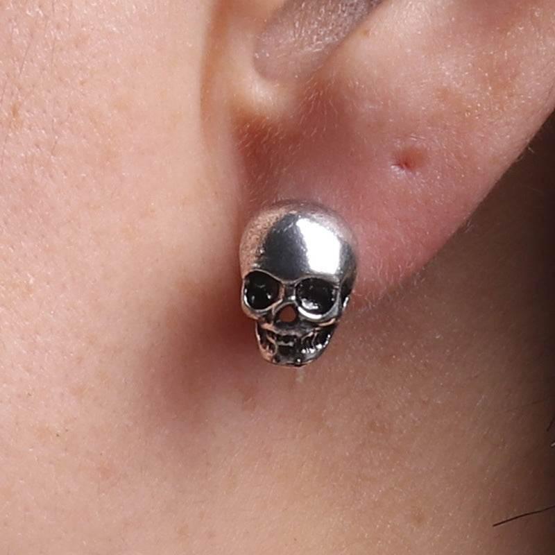Silver skull stud earring for women, gothic fashion accessory on ear close-up