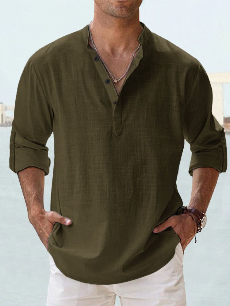 Man wearing an olive green shirt with rolled-up sleeves against a light blue background
