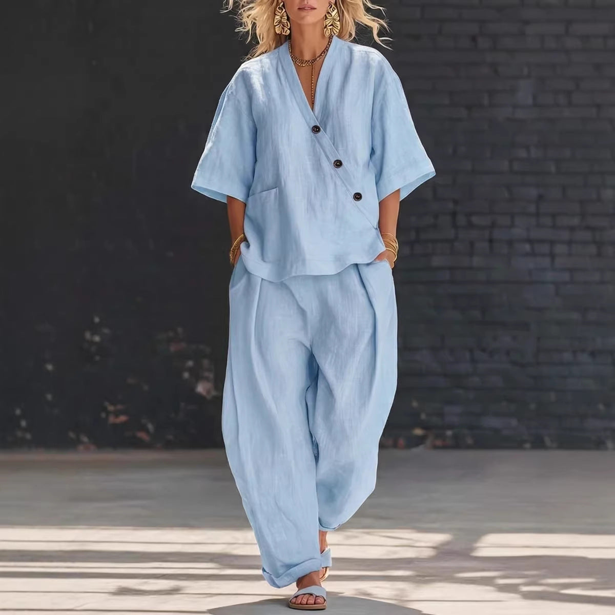 Woman wearing a light blue outfit against a dark brick wall.