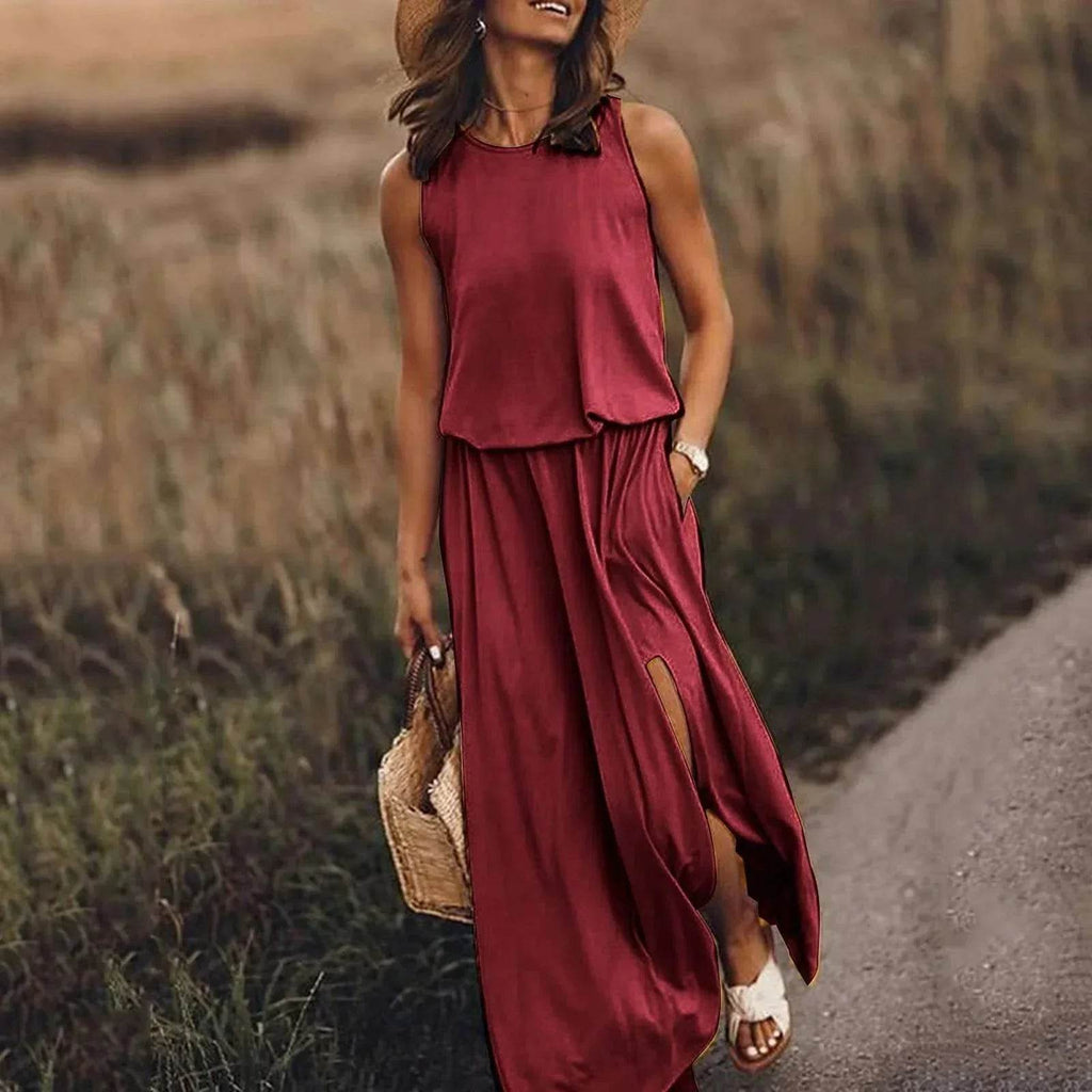 Woman in sleeveless burgundy maxi dress with side slit and straw hat outdoors