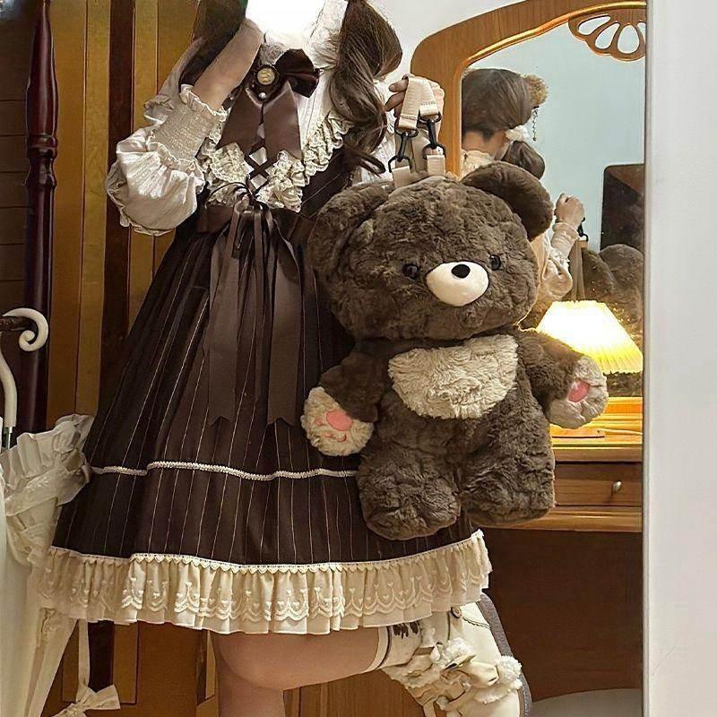 Woman in vintage brown lace dress holding large plush teddy bear bag in elegant bedroom