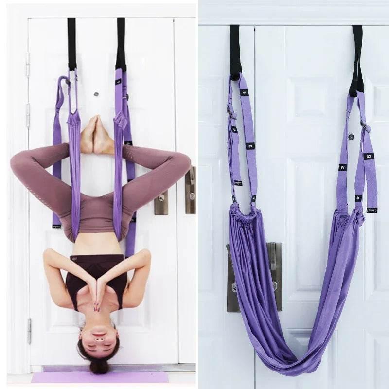 Woman using a purple yoga inversion swing for stretching at home, aerial yoga fitness hammock