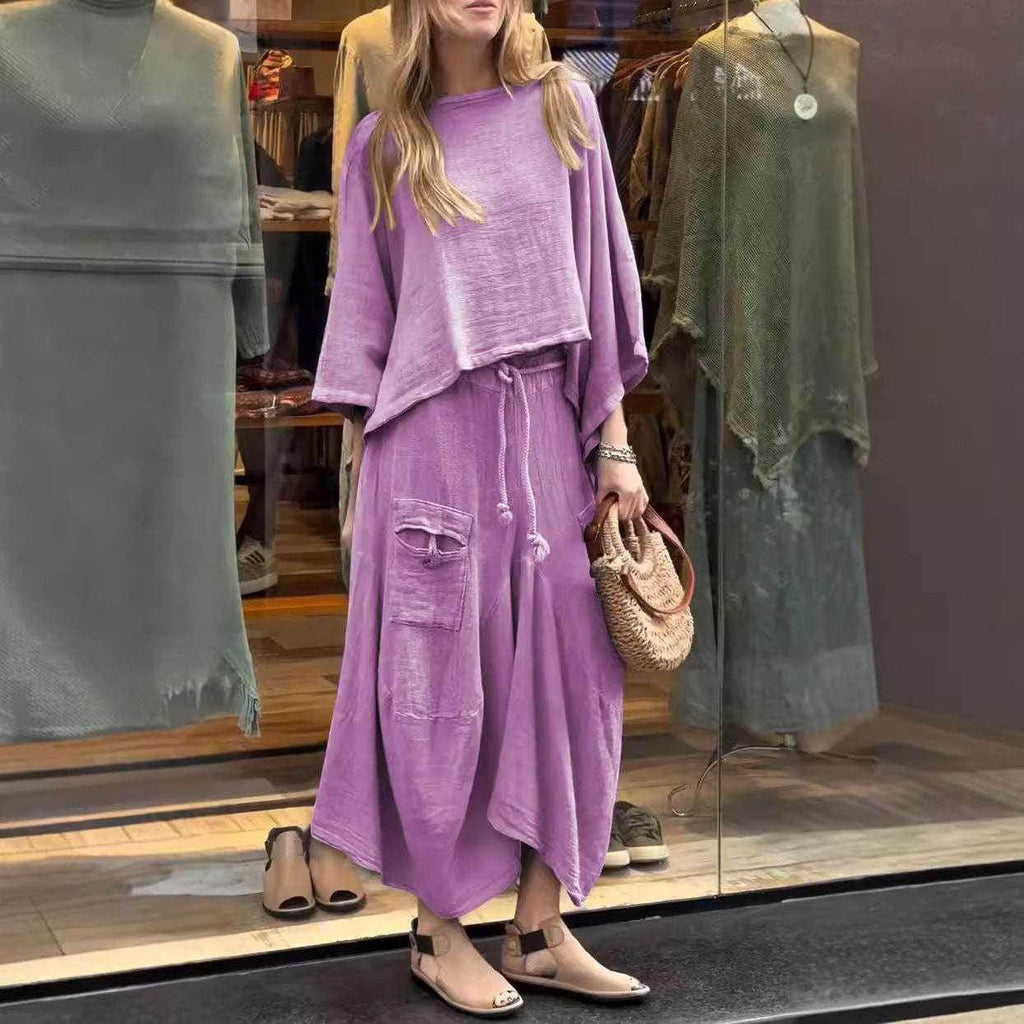 Woman in loose lavender lounge set with drawstring skirt and sandals, holding woven bag, outside clothing store