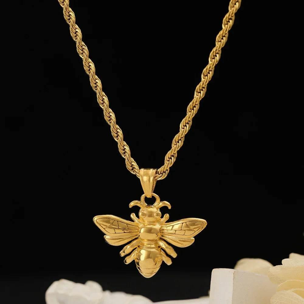 Gold bee pendant necklace with rope chain on black background, stylish women's jewelry