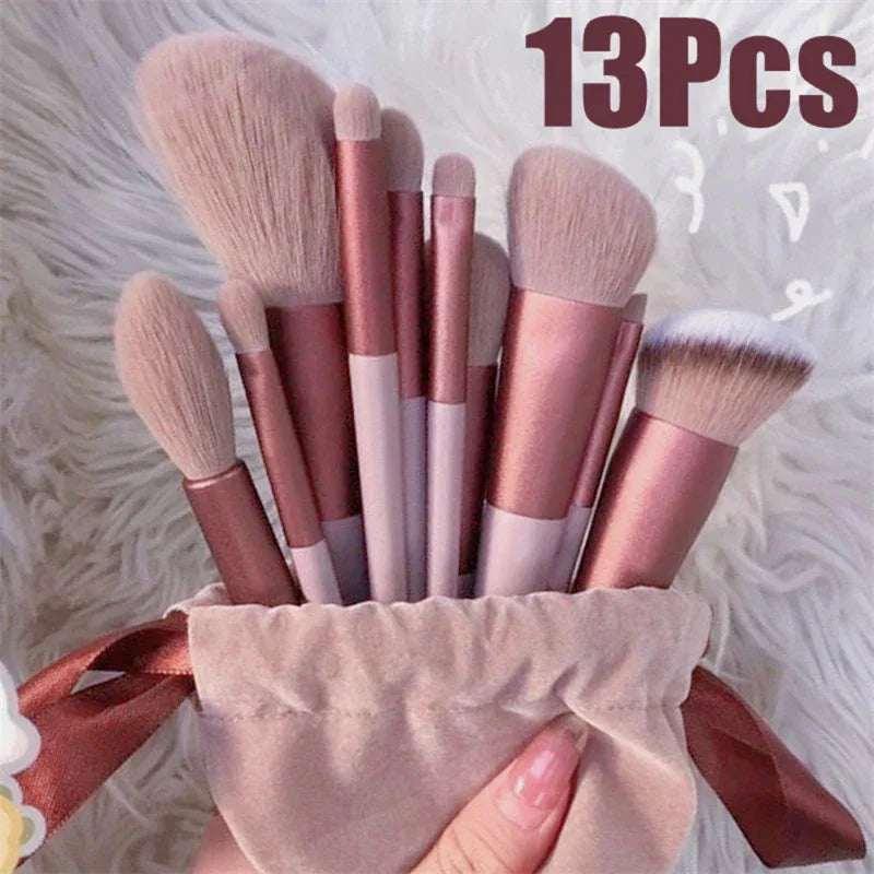 Set of 13 rose gold makeup brushes in a velvet pouch on a fluffy white surface