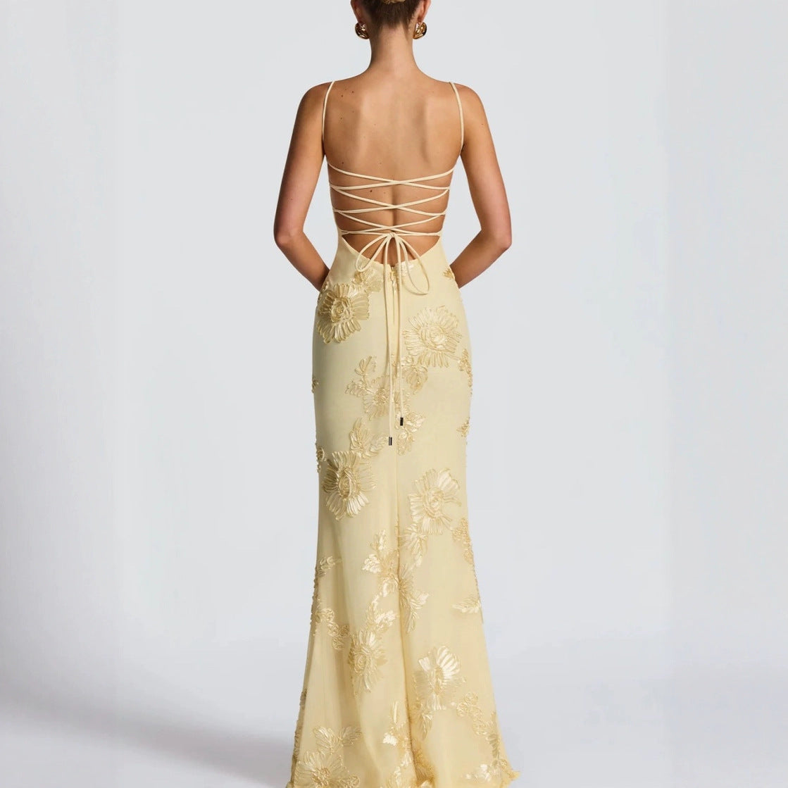 Yellow evening gown with intricate back design on a white background