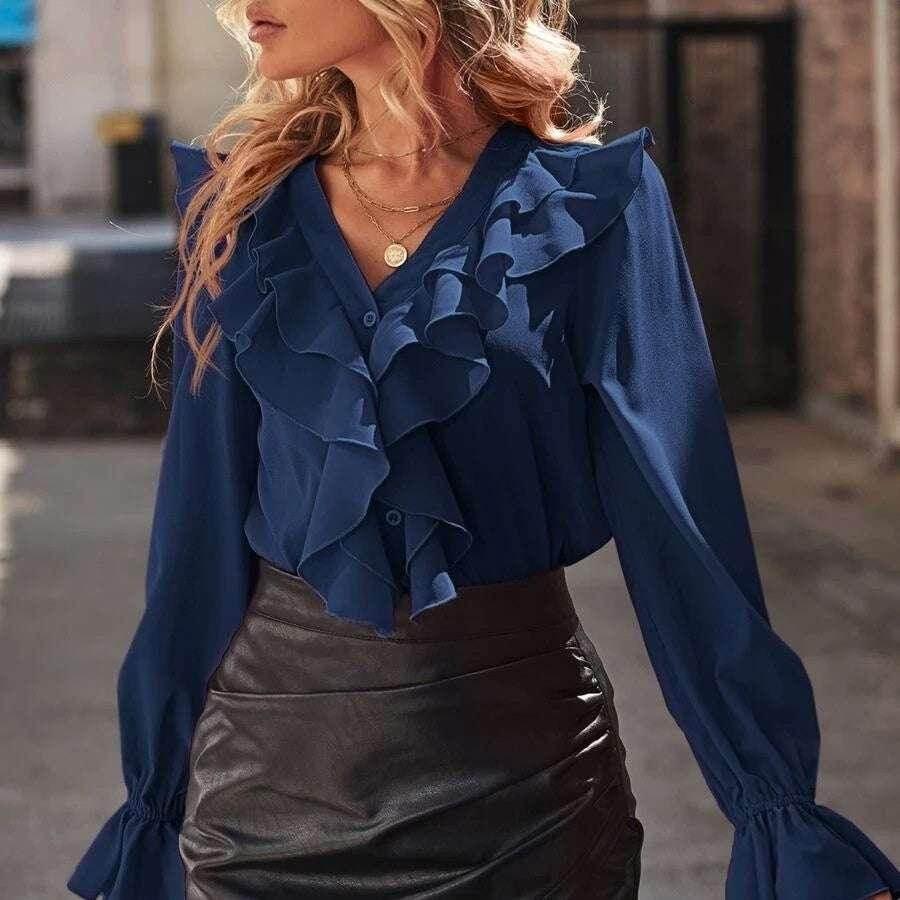 Woman wearing navy ruffle blouse with long sleeves and black faux leather skirt, chic outfit