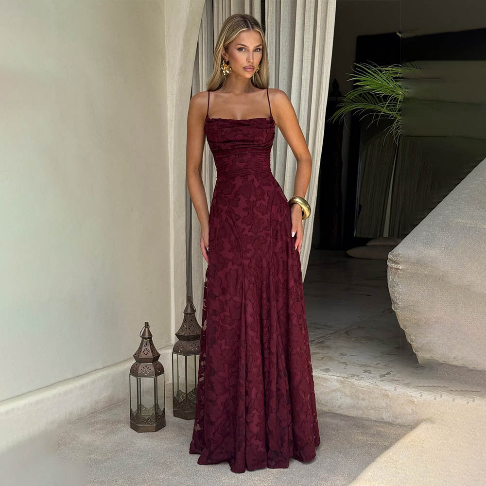 Woman in a burgundy evening gown standing in an elegant indoor setting.