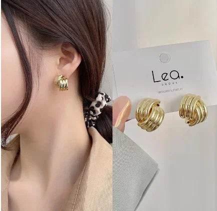 Woman wearing chunky gold hoop earrings, shown close-up and on a display card.