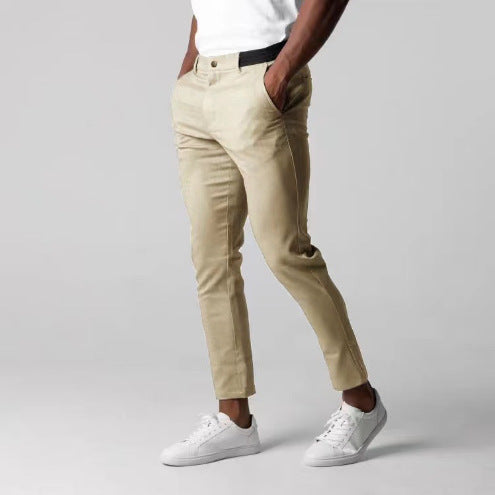 Person wearing beige pants and white sneakers on a plain background