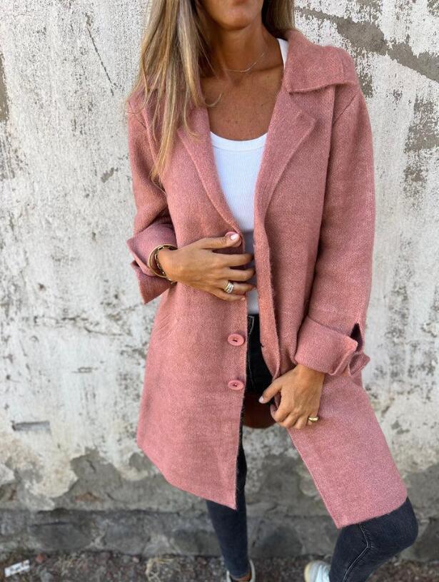 Woman wearing a trendy pink textured overcoat, white top, and dark jeans outdoors