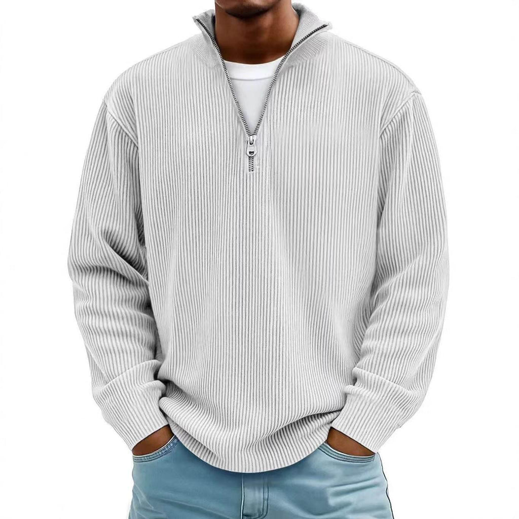 Man wearing a light grey ribbed half-zip pullover sweater and casual blue pants