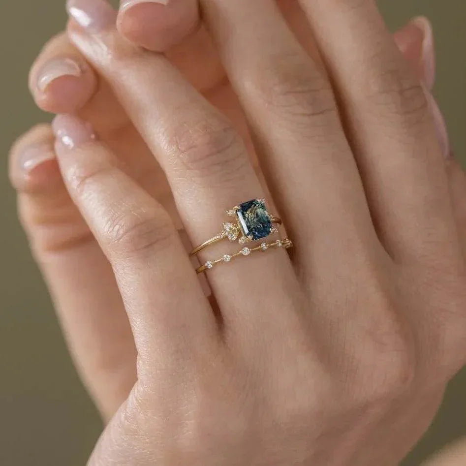 Woman’s hand wearing a gold ring with blue gemstone and diamond accent stacking ring