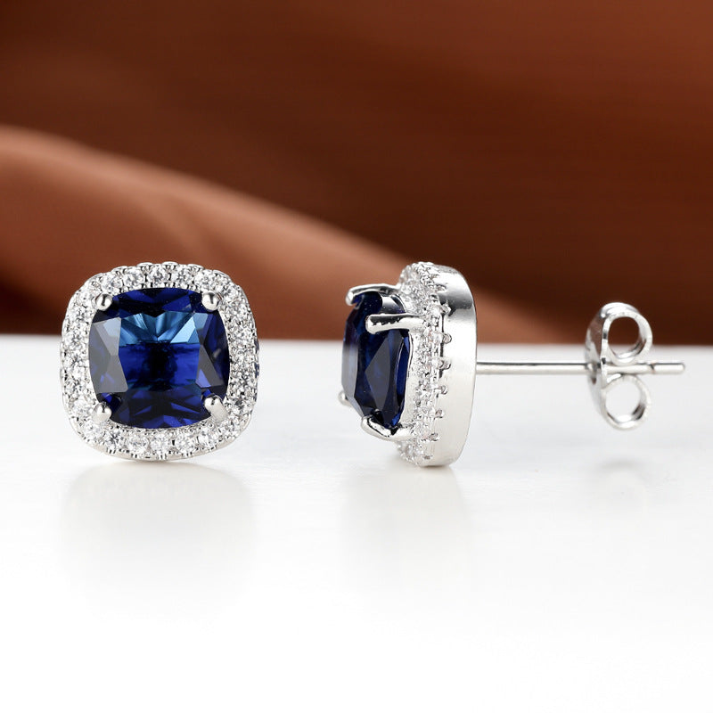 Pair of blue gemstone earrings with silver setting on a white surface.