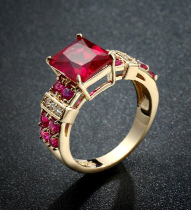 Gold ring with a large red gemstone on a dark background