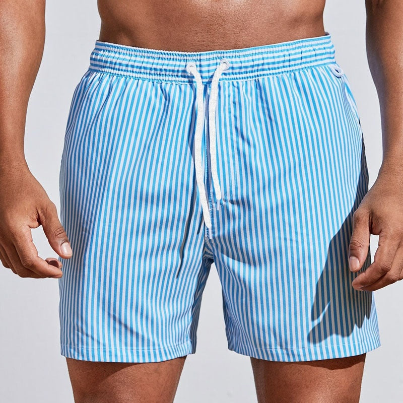 Blue and white striped swim shorts on a person against a light gray background