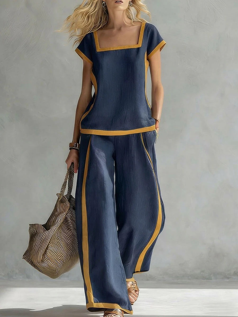 Woman wearing a navy outfit with gold trim holding a bag against a gray background