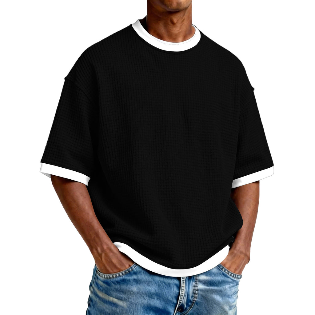 Person wearing a black t-shirt with white trim and blue jeans on a white background