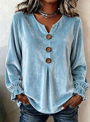 Light blue long-sleeve top with wooden buttons worn by a person against a neutral background