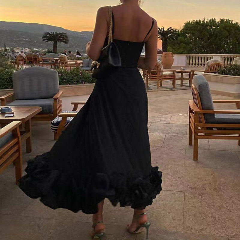 Woman in a black dress standing on a patio with a scenic view at sunset.