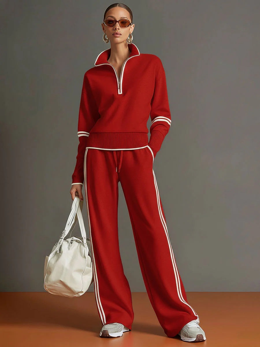 Person wearing a red tracksuit with white stripes, holding a white bag against a gray background.