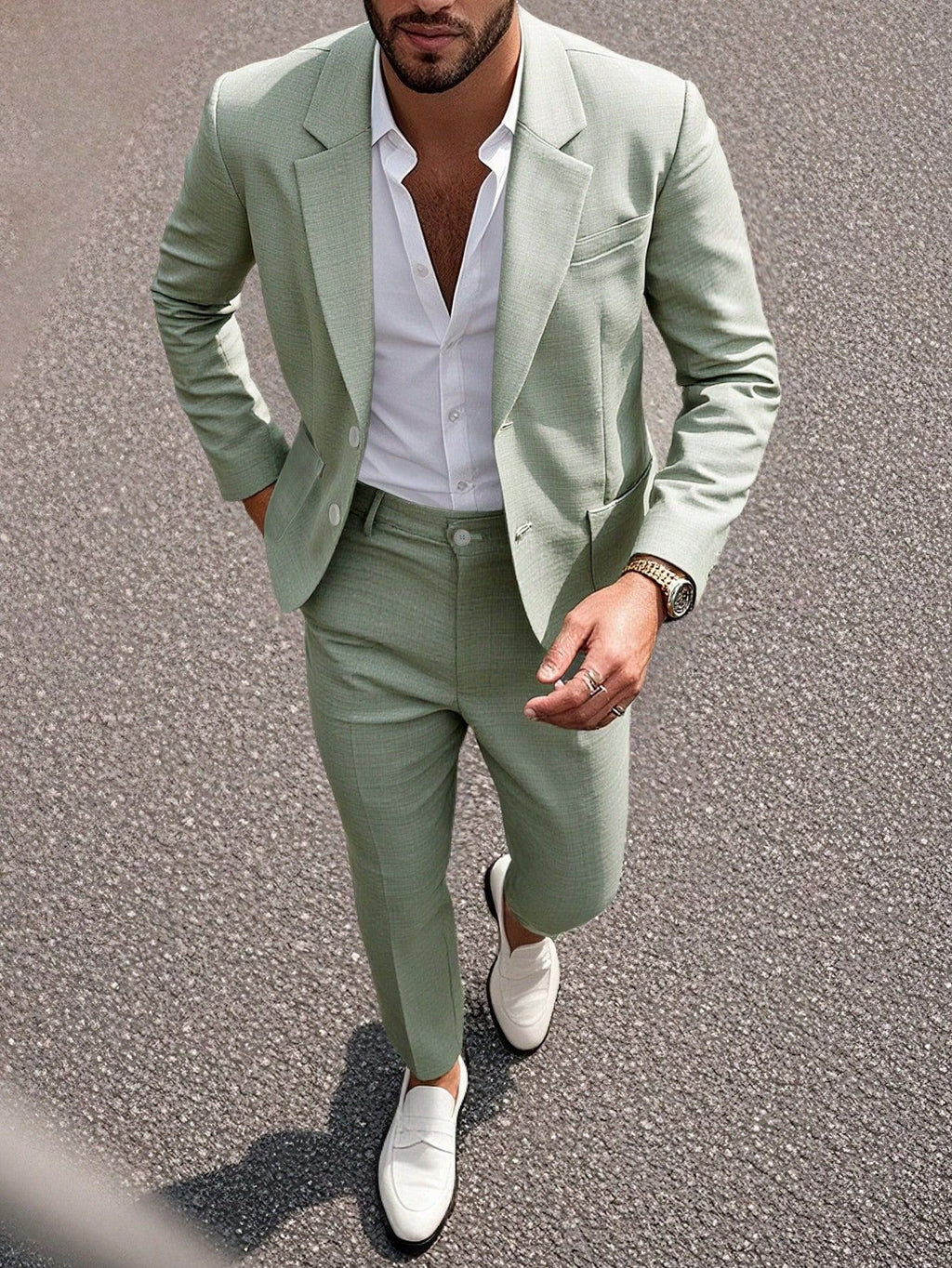 Man wearing a light green suit with white shirt and shoes on a road.